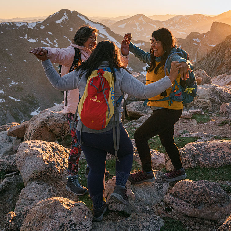 Tres mujeres celebrando en la cima de una montaña