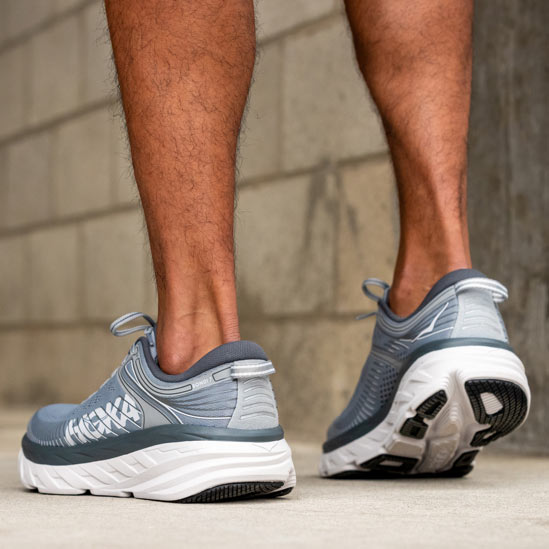 Close up of someone standing, wearing HOKA Bondi 7 shoes