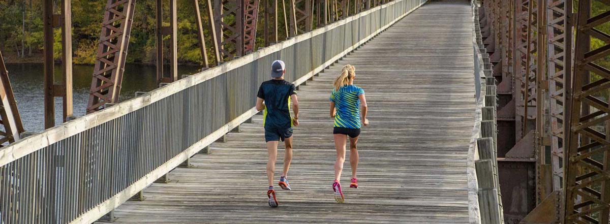 Three people running on a bridge