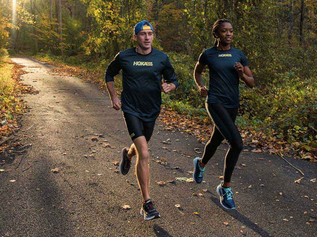 two people running down a forest road
