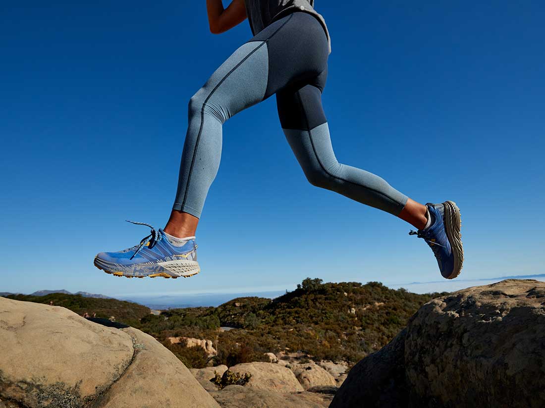 A woman jumping over rocks