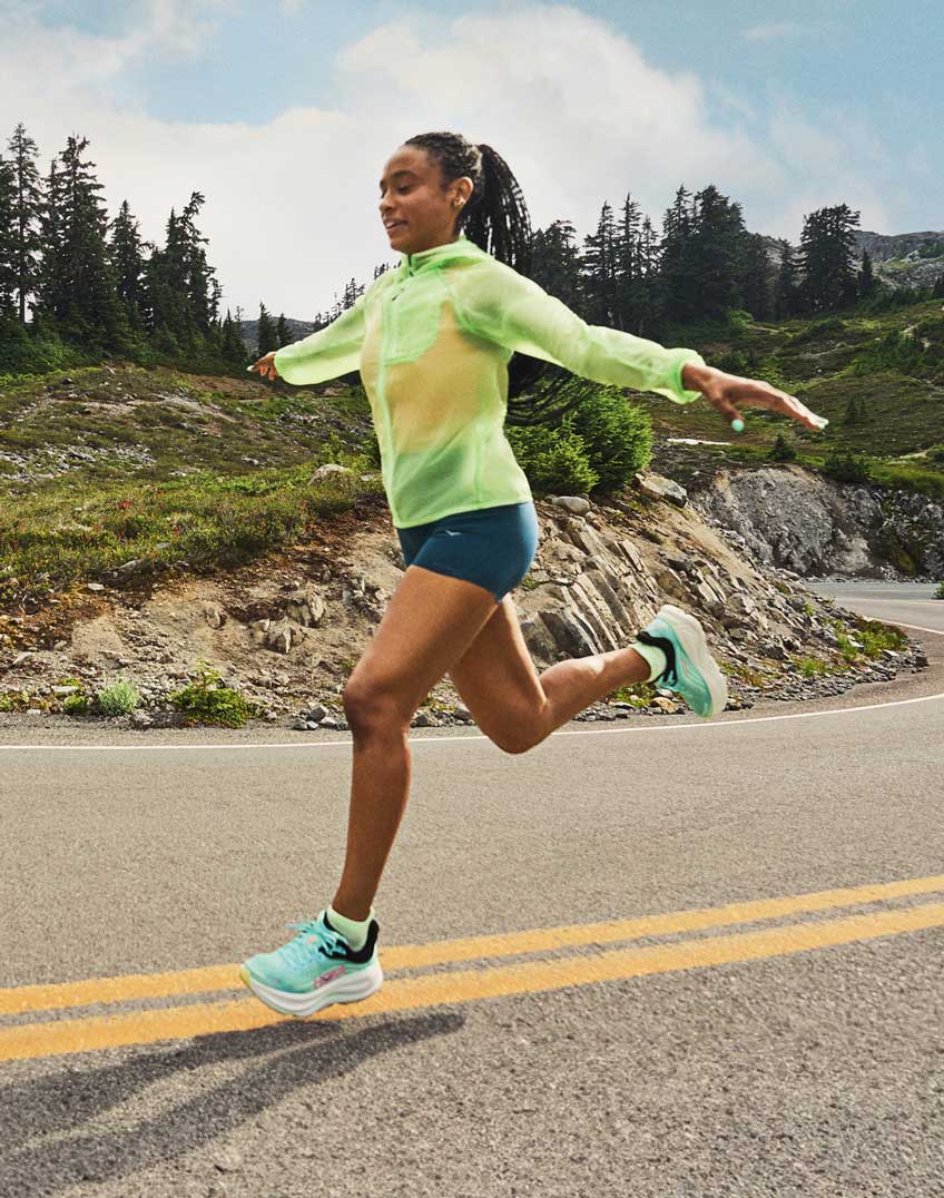A woman runner showing off her HOKA shoes.