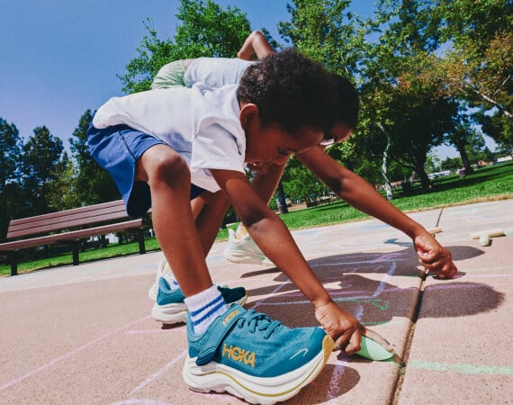 Un enfant jouant sur une aire de jeux qui porte des chaussures HOKA.