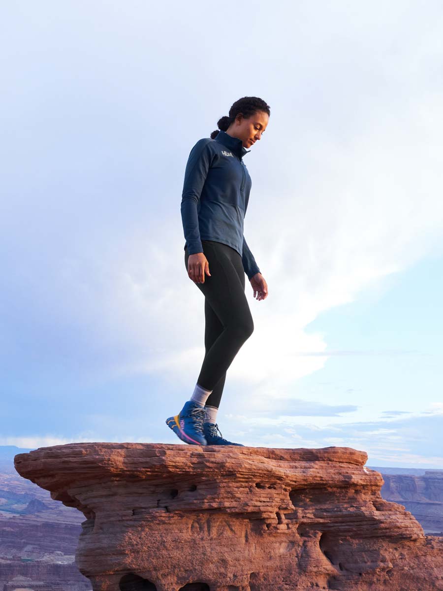 Woman standing atop rock overlooking the Grand Canyon.