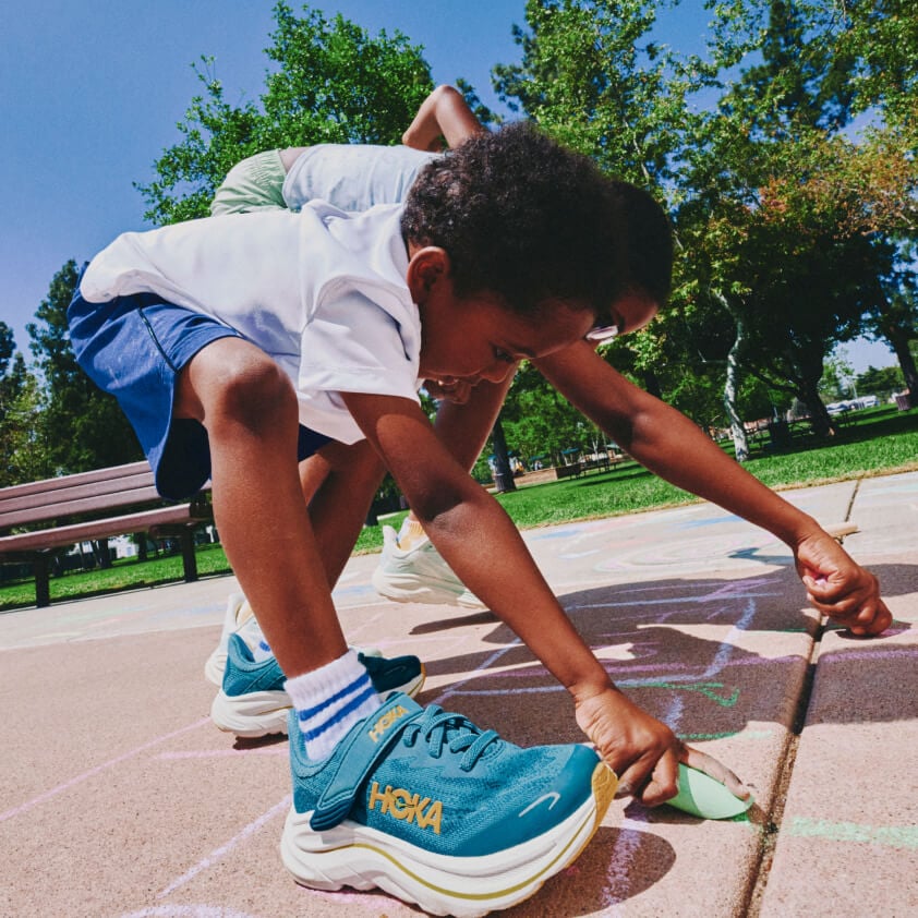 Un enfant jouant sur une aire de jeux qui porte des chaussures HOKA.