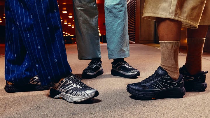 Gros plan sur les pieds de trois personnes portant des chaussures HOKA.