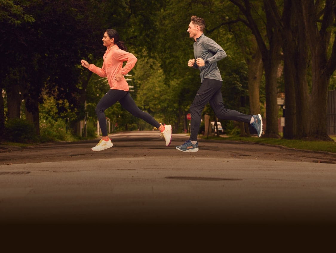 Deux coureurs traversant une route avec de l'équipement HOKA.
