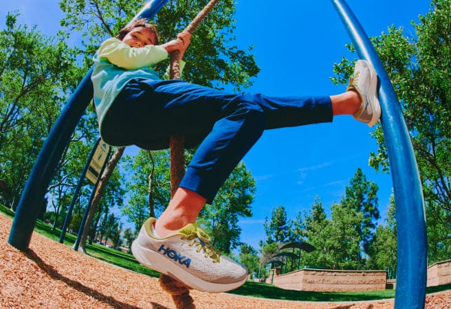 Un enfant jouant sur une aire de jeux qui porte des chaussures HOKA.