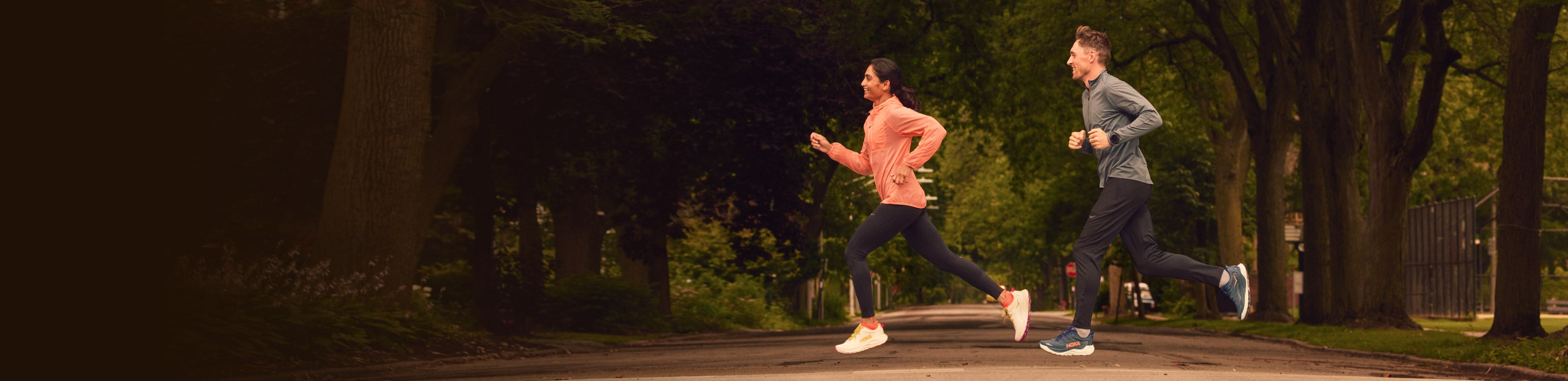 Deux coureurs traversant une route avec de l'équipement HOKA.