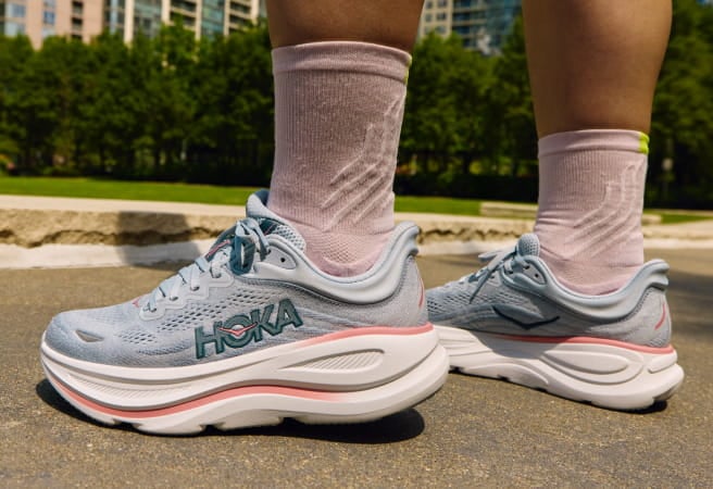 Gros plan des pieds d’un mannequin, portant des chaussures de course HOKA.