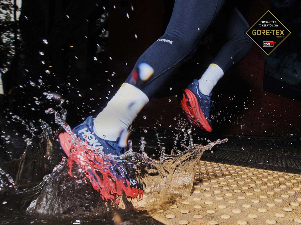 Personne sautant dans une flaque d’eau avec des chaussures HOKA.