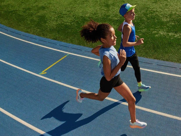 Two kids running on an outdoor track, wearing HOKA shoes.