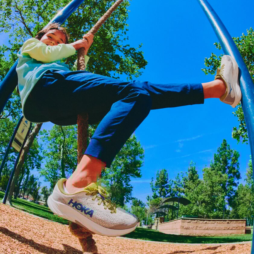 Un enfant jouant sur une aire de jeux qui porte des chaussures HOKA.