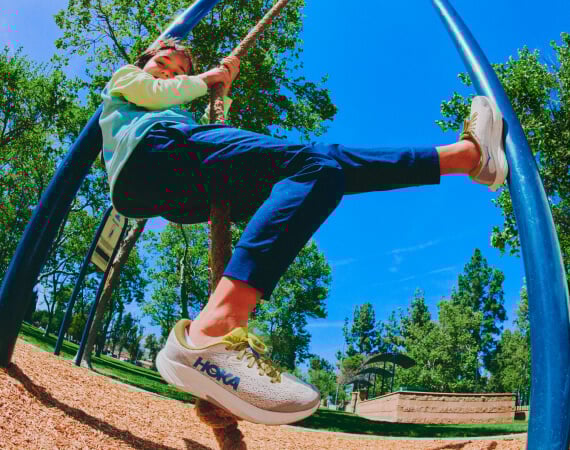 Un enfant jouant sur une aire de jeux qui porte des chaussures HOKA.
