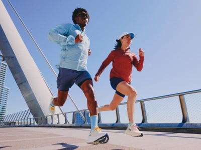 Personne courant à travers les nuages, portant des chaussures de transport HOKA.