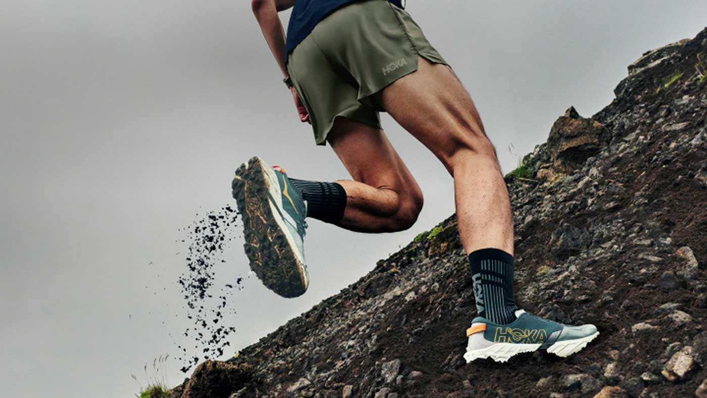 Gros plan des jambes d’un coureur portant des Speedgoat.